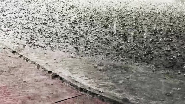 Torrential rain falling from a storm flooding a city street in South Beach, Miami, Florida