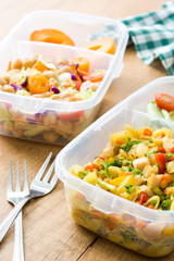 Healthy meal prep containers with food ready to eat.Chickpea salad on wooden table. Top view. Copyspace