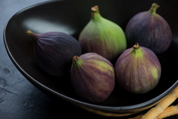 Close-up of ripe fig fruits served in a black bowl, selective focus, studio shot