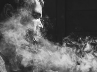 Portrait of young male bathers closeup. Releases steam from e-cigarette