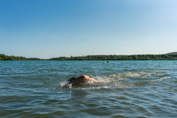 Fototapeta premium Man swimming in a lake, open water swim in summer