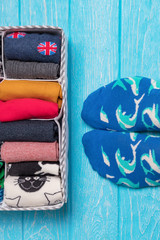 Box with different colorful socks. Feet selfie and a socks organizer on a blue background. Top view, free space