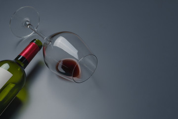 close up of a red wine glass and an empty bottle of red wine on the table
