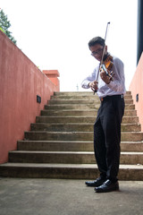 man playing violin in a hall with stairs