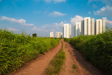 Long dirt road towards the city, rural to urban concept