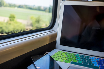 closeup of laptop portable office station inside a train during a travel for work or vacation, internet mobile with wifi and hot spots. modern lifestyle for traveler and workers