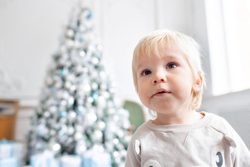 Portrait little boy. Happy new year. decorated Christmas tree. Christmas morning in bright living room. sitting on green chair