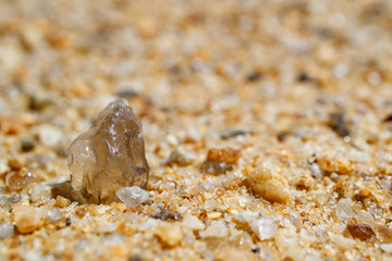 transparent stone on bright summer coastal sand, sand and stone