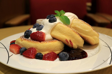 Mouthwatering Fluffy Souffle Pancake with Fresh Whipped Cream and Mix Berries Served on white Plate 