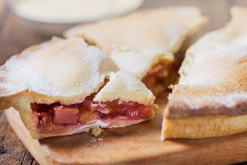 Piece of fresh rhubarb and strawberry pie with cream nearby
