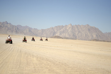 a group of people on quad bikes in the desert