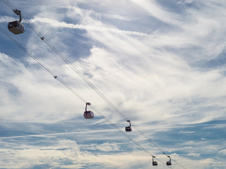 Ropeway with wagons on a background of blue sky with clouds.