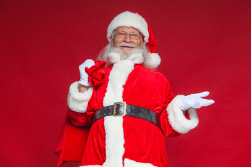 Christmas. Smiling Santa Claus held out his empty hand with his palm up, and in the second hand he...