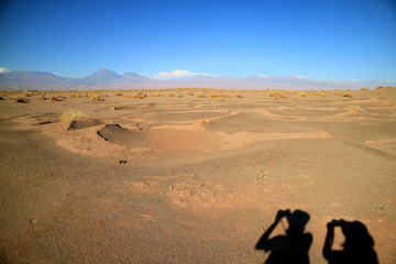 Fototapeta na wymiar Shadow of two tourist on the ground of Aldea de Tulor ancient village complex, San Pedro de Atacama of Chile