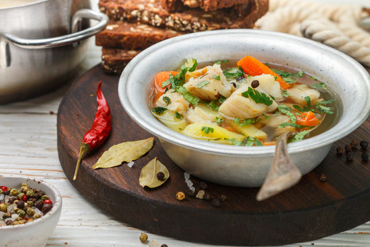 Fresh white fish soup with carrots, potatoes, onions, herbs and spices. Rustic style