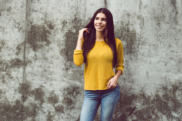 Lovely beauty. Beautiful young woman looking away with smile while standing against concrete background outdoors 