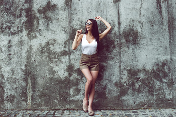 Fototapeta na wymiar Sexy mood today. Full length of beautiful young woman looking away with smile while standing against concrete background outdoors 