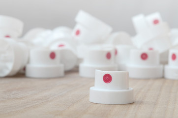 Several new plastic nozzles from a paint sprayer that lie on a wooden surface against a gray wall...