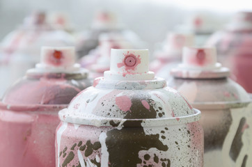 A lot of dirty and used aerosol cans of bright pink paint. Macro photograph with shallow depth of...