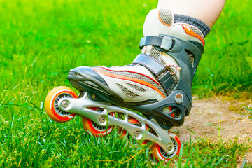 Closeup inline skates in the green grass. In-line skating