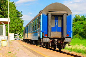 Fototapeta na wymiar Blue rail wagon waits at the platform for passengers. Rail transport in the Czech Republic. Empty platforms at the regional station. A sunny day on the railroad.