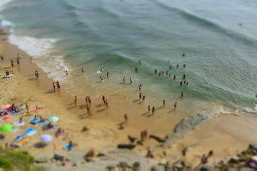 People bathing in the sun, swiming and playing games on the beach. Tourists on the sand beach of Portugal coast