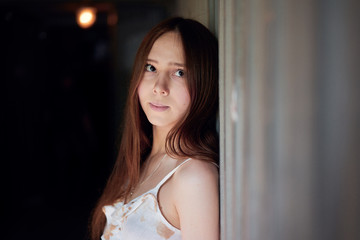 Naklejka premium Young girl portrait by the wall in the dark, outdor