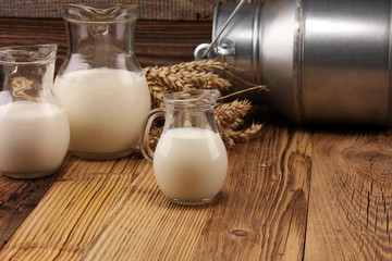 A jug of milk and glass of milk on a wooden table