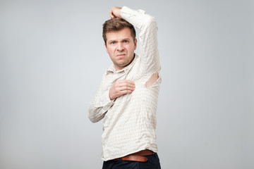 A young handsome man accidentally tore his shirt on his armpit.