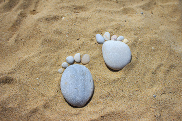 Fototapeta na wymiar Stone foot symbol on sea sand