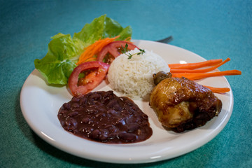 Brasileirinho - Brazilian made typical dish of beans with rice with salad of lettuce, tomato and carrot and roast chicken.