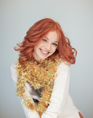 Beautiful woman with perfect red curly hair and make up in a wintry christmas knit sweater, golden...