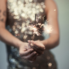 woman in glitter dress holding sparkler, close up hands, romantic look, can be used as background