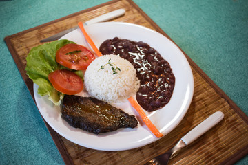 Brasileirinho - Brazilian made typical dish of beans with rice with salad of lettuce, tomato and carrot and steak.