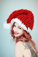 Santas little helper. Beautiful happy young woman with a santa claus hat, perfect make up, red lipstick, can be used as background