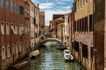 Venice, Italy, the lagoon town, viewing old alleys along small canals with historic buildings at a sunny day in summer.