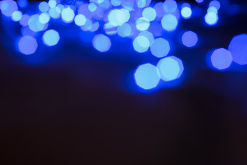 abstract unfocused background blue color illumination glares and sparkles with bokeh effect from garland lamps holidays decoration in dark environment and empty copy space for your text