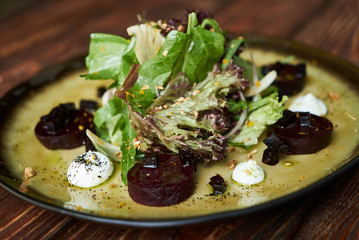 Fototapeta na wymiar Fresh Beet Salad with Goat Cheese, Candied Walnuts, Spring Greens, and Herbs. Healthy diet and Vegetarian food