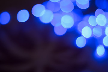 abstract unfocused background blue color illumination glares and sparkles with bokeh effect from garland lamps holidays decoration in dark environment and empty copy space for your text