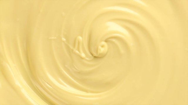 White molten chocolate swirl rotated background. Melted chocolate abstract curves backdrop. Creamy texture sweet rotation background close-up. Confectionery. 4K UHD video 3840x2160