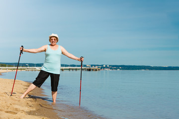 Senior woman practicing nordic walking on beach