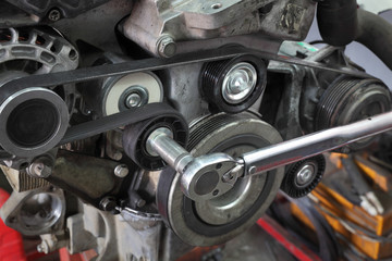 Fototapeta na wymiar Pk belt, pulleys and alternator at modern car engine after servicing with ratchet tool