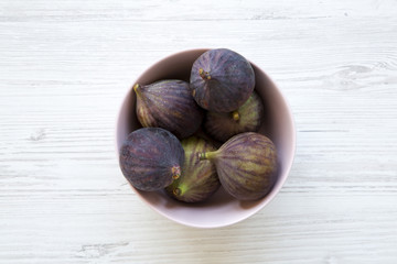 Fresh figs in a pink bowl on a white wooden table. Top view, overhead, from above.