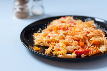 A plate of roasted vegetable pasta bake on a pale blue surface