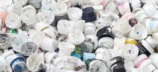 A large number of caps from cans of aerosol paint for graffiti. Smeared with colored paint nozzles...
