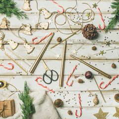 Fototapeta na wymiar Getting ready for Christmas or New Year celebration party. Flat-lay pattern of holiday decoration objects, toys, candles, candy canes, tree branches over white background, top view, square crop