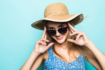 Close-up of pretty joyful girl in straw hat ready for journey posing over blue background.