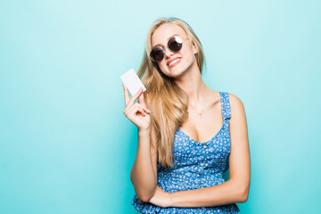 Smiling young woman in sunglasses hold credit card on blue background.