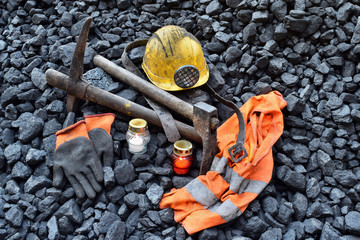 Vigil light, candle with the miner belongings (helmet, gloves, pickaxe, vest, belt) - obrazy, fototapety, plakaty