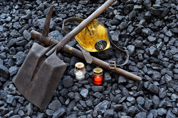 Vigil light, candle with the miner belongings (helmet, pickaxe, shovel, belt) - obrazy, fototapety, plakaty